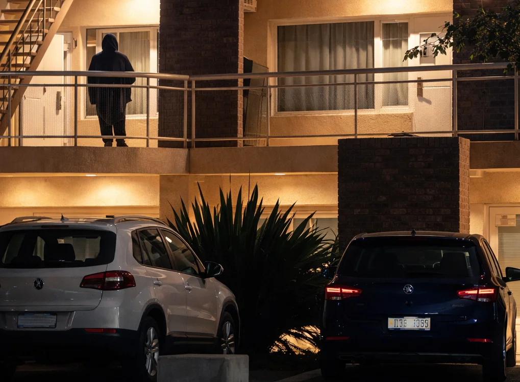 Figura encapuchada en el balcón nocturno