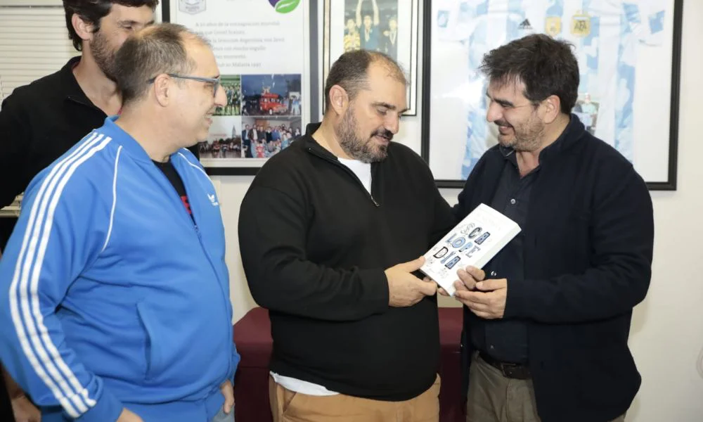 Mauro Scaloni recibiendo el libro de la mano de sus autores, Javier Acuña y Matías Bauso